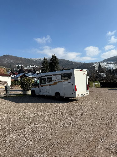Wohnmobil auf Winterreise im Schwarzwald mit Bergen im Hintergrund.